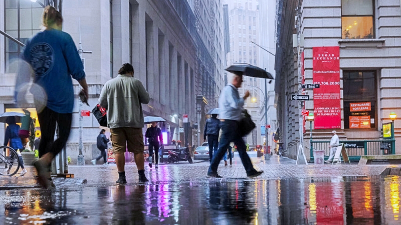 人们在雨中走过纽约证交所前的道路。（Getty Images）