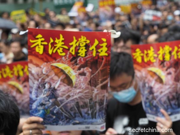 7月7日，23万香港人参加了九龙“反送中”游行，游行人士手持《看中国》印刷的“香港撑住”画报。