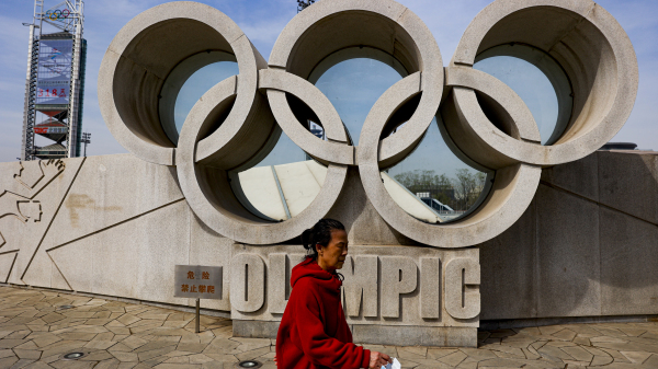 一名女子在北京奥林匹克公园走过五环标志。