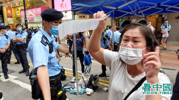 一位在铜锣湾和朋友购物的女士忽然被警方票控，指她违反限聚令。她气愤不已。