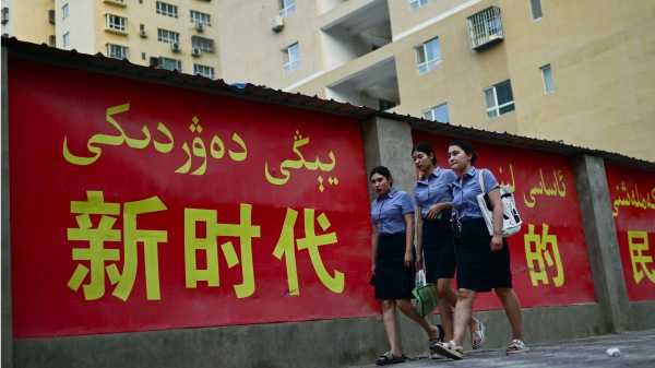 2023年7月18日，新疆喀什地区叶城县，行人走过用汉语和维吾尔语写成的“新时代”宣传标语。