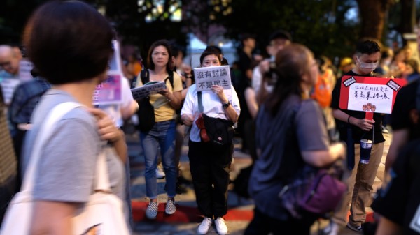 现场无数民众带着自制展板来到现场。图片是一名年轻女性手举“没有讨论，不是民主”，图右则是一名年轻男性手持“你以为我很爱来青岛东路吗”。