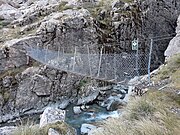 Photo of a swing bridge with steel netting over a gorge river