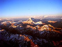 Puncak gunung, dengan awan di kejauhan.