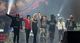 Guns N’ Roses на сцене Олимпийского стадиона в Лондоне 16 июня 2017 года. Слева направо: Диззи Рид, Ричард Фортус, Дафф Маккаган, Эксл Роуз, Слэш, Мелисса Риз, Фрэнк Феррер[англ.]