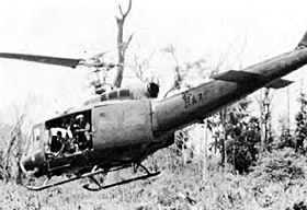 Military helicopter with main door open, over jungle