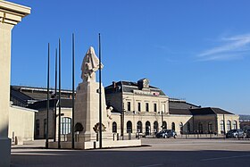 Bâtiment horizontal, avec devant un parvis et une statue dans la pelouse.