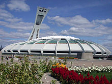 Stade blanc en forme de dôme devant un champs de fleures.