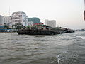 Barges chargées de matériaux affleurant l'eau devant l'Hôpital Siriraj et l'Université Mahidol à Bangkok