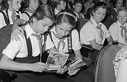 Two girls seated in a theatre looking at a brouchure