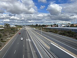 View from a bridge of an under construction railway line in the median of a highway