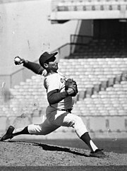 a baseball pitcher on the mound and in full-stride, throwing towards home plate