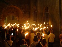 Photographie en couleurs d'un défilé au flambeau, la nuit.