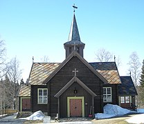 Foto einer dunkelbraunen Holzkirche mit einem verzierten Eingang