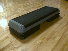 One step aerobics device resting on a wooden floor.