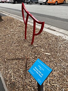 A red bike rack in the abstract shape of devil horns