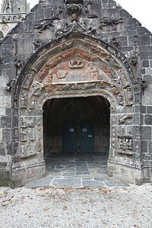 At the top of the porch gable we see two kneeling angels and below them the two "floating" angels. Above the entrance is a tympanum depicting the Nativity. The Virgin Mary lies on a bed with Joseph sat at the foot of the bed. The heads of two cattle peer out from the wall above the Virgin Mary. A previous rector had had the main part of Mary's body chiseled away as it was thought inappropriate. In the voussures and piédroits we can see several angels and other depictions and at the base of the right hand side we can see the depiction of the Adoration of the Magi. At the far end of the porch we can make out the two doors giving access to the church.