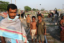 People looking at camera, shacks behind them