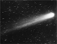 Black-and-white picture of the comet, its nucleus brilliant white, and its tail very prominent, moving up and to the right