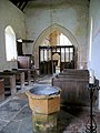 L'intérieur de l'église, avec un baptistère, des bancs et une chaire.