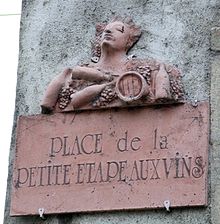 Plaque de rue en terre cuite rouge, avec personnage, raisins, bouteilles et tonneaux