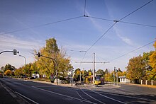 Straßenkreuzung, bei der links die Karlsruher Straße und rechts die Endhaltestelle der Linie 3, einer Haltestelle, an der ein Straßenbahnzug steht.