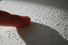 finger tip touching page with raised dots