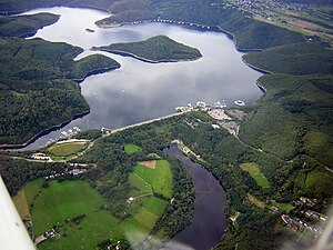 Rurtalsperre Schwammenauel (Blickrichtung Westen) mit Staudamm (Vordergrund Mitte), Halbinseln am Tonsberg (linke Bildmitte) und Eschauel (hinten rechts) sowie Insel Eichert (Bildmitte)