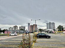 A imagem mostra alguns dos edifícios do bairro Jardim Finotti, Zona Leste, vistos do estacionamento de um supermercado atacadista no bairro vizinho Carajás, que fica na zona sul