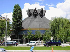 L'extérieur de l'église Saint-Jean telle que visible à partir des années 1980. La partie inférieure date de la création initiale en 1965 et le toit a été modifié et réinterprété en 1979.