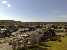 Luftaufnahme eines Dorf, im Vordergrund eine Esso-Tankstelle, weiter entfernt ein Fluss, über den eine Straßenbrücke führt