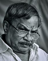 A black and white photograph of an old man wearing glasses.