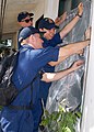 Sailors assigned to the dock landing ship USS Tortuga (LSD 46) replace a protective window screen at Kalalake Elementary School during a community service project