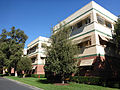 Three story building with green stripes surrounded by some trees