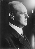 Portrait of a man wearing glasses, a jacket and a tie.