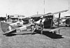 Two pilots of No. 7 EFTS RAAF discuss the day's flying next to their Tiger Moth training biplanes.