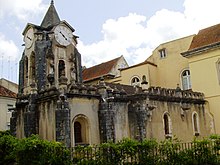 Igreja de Nossa Senhora do Pópulo (Church of Our Lady of the Populace). Aged façade, darkened in places. Prominent clocktower