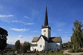 Foto einer weiß gestrichenen gemauerten Kirche mit einem Friedhof