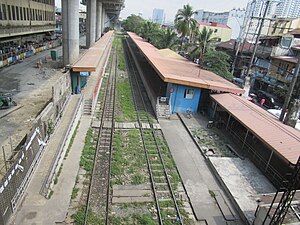 Railway station with 2 side platforms as seen from above. The station has an orange roof and blue walls.