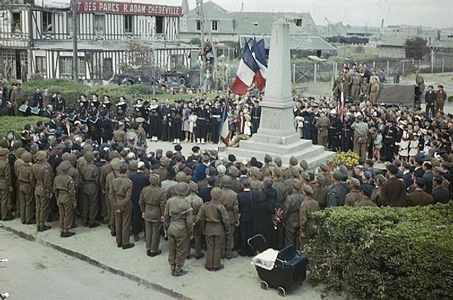 La cérémonie officielle au monument aux morts de Courseulles-sur-Mer le 14 juillet 1944, jour de la fête nationale, en présence de la population locale et de militaires de l’Armée française de la Libération et d’unités alliées.