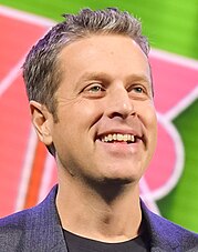 A man with brown hair smiling to the right