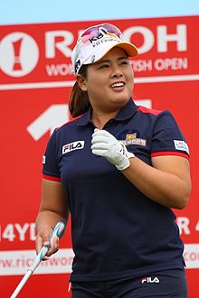 Golfeuse serrant son poing gauche ganté, lunettes et casquette sur la tête.