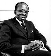 A black and white photograph of man sitting in the chair wearing suit