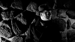 black and white photograph of a man wearing an overcoat and fedora hat