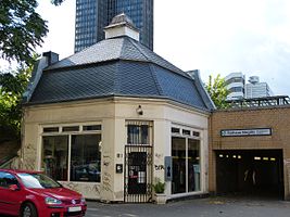 Ostausgang des S-Bahnhofs zur Berlinickestraße mit dem denkmalgeschützten Verkaufspavillon von 1910. Hinter der Dachspitze ist das Hochhaus des Steglitzer Kreisel zu erkennen.