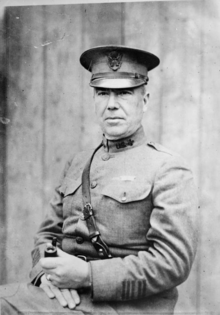 A man, seated, in a military officer's uniform