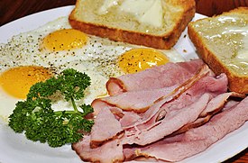 Ham and eggs served with thinly sliced ham and fried eggs prepared "sunny side up", served with toast