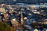 Foto einer an einem Fluss gelegenen Stadt, mit einer Kirche im Vordergrund.