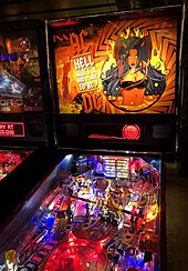 Pinball machine in the style of AC/DC. The artwork shows the AC/DC logo in between the words "Hell Ain't a Bad Place to Be" with the logo's high voltage symbol at the beginning and end of the words, and a hand-drawn woman with black hair, devil horns and a black bikini, standing in lava with fire in the background.