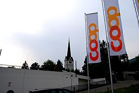 Rigardo de la parkloko de Coop-supermerkato en la centro de Wangen ĉe Olten al la preĝejo